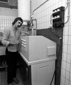 880102 Portret van Wim Quakernaat van de Gemeentelijke Fotodienst, bij de Kodak-ontwikkelmachine in de donkere kamer ...